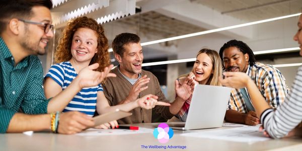 A diverse group happily collaborating around a laptop in a modern workspace.