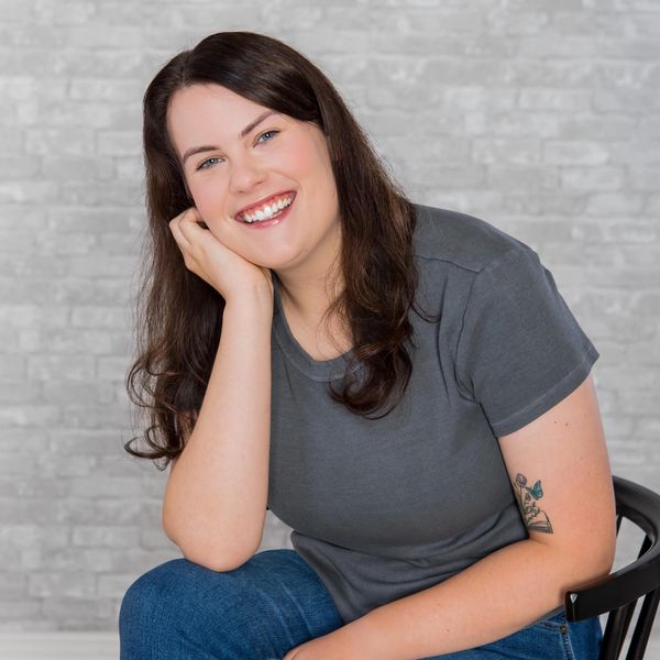 Smiling woman with dark hair and a tattoo on her arm.
