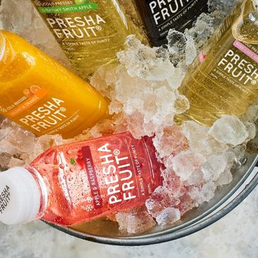 Bottles of Presha Fruit juice chilled in ice in a bowl.