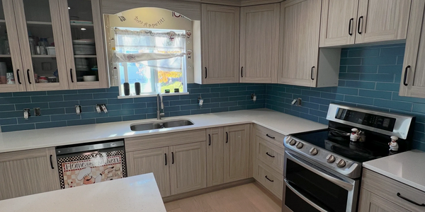 Modern kitchen with light wood cabinets and blue tile backsplash.