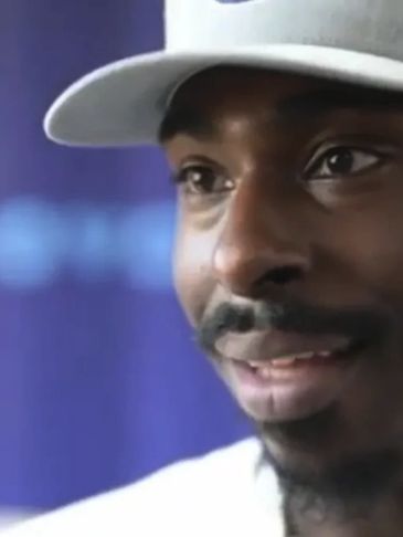 Close-up of a man wearing a white cap, smiling gently.