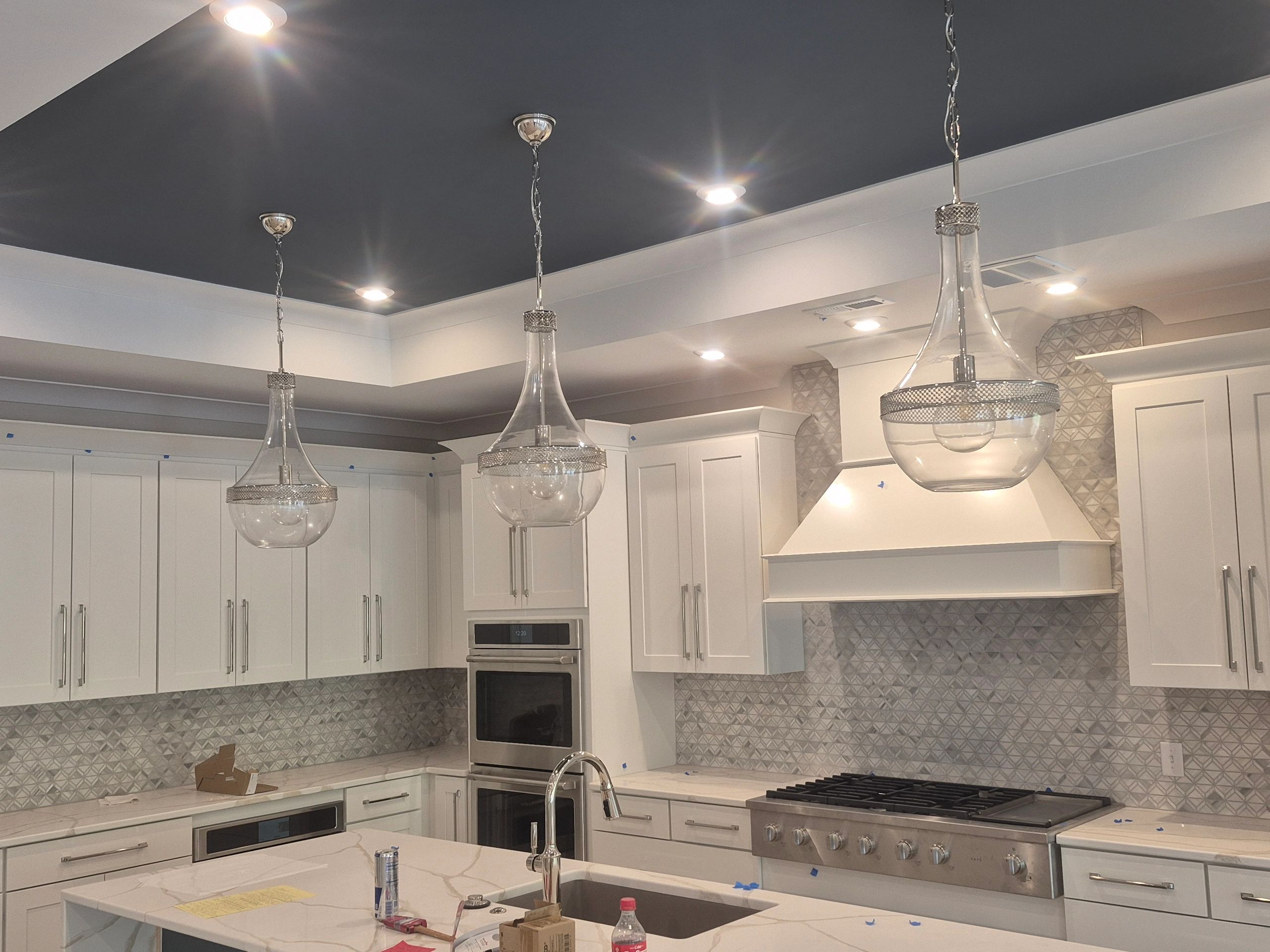 Modern kitchen with white cabinets and pendant lights over island.