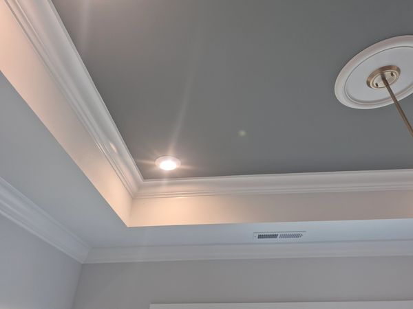 Gray tray ceiling with white trim and recessed lighting.