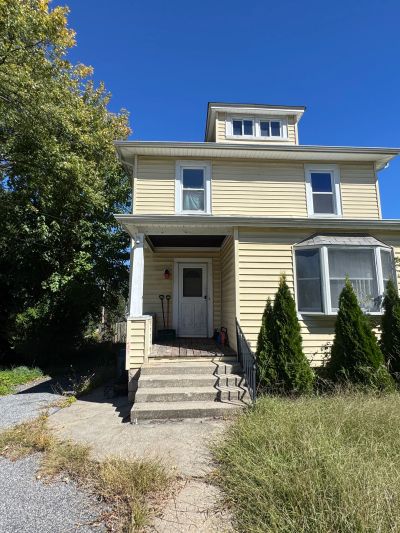Yellow two-story house under clear blue sky.