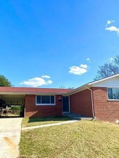 Single-story brick house with a small lawn under clear blue sky.