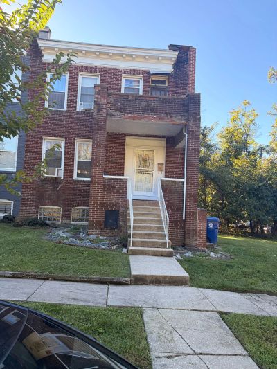 Brick two-story house with front steps and white door.