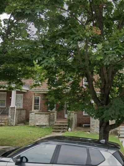 Tree overshadowing a car in front of brick houses.