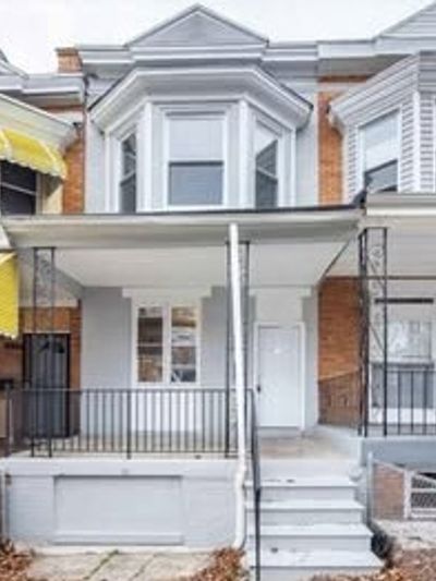 Front view of a white-painted townhouse with a small porch and steps.