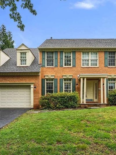 Two-story brick house with green shutters and a spacious front lawn.