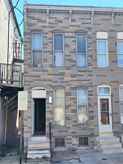 Two-story brick row house with multiple windows and stairs leading to front doors.