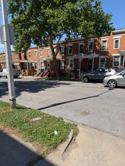 Row of brick townhouses with parked cars on a sunny day.