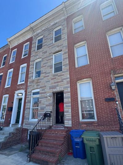 Person entering a brick row house with blue sky above.