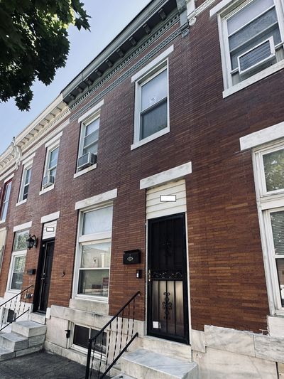 Row of brick townhouses with black doors and white trim under a clear sky.