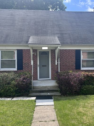 Brick house entrance with blue shutters and a small porch.