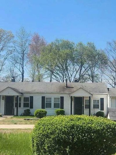 A single-story white house with black shutters under a clear blue sky.