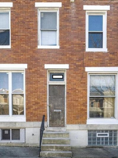 Old brick building with a weathered door and steps.