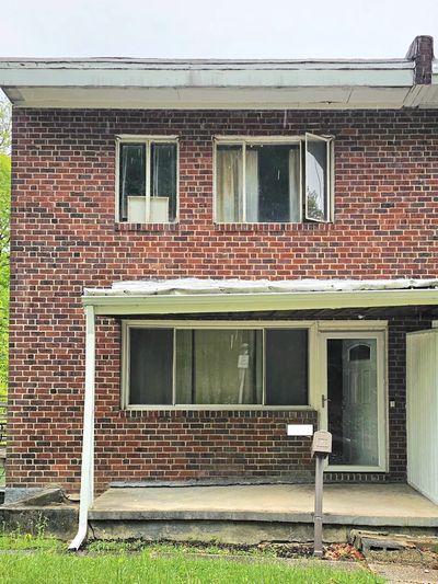 Two-story brick house with a small covered porch and mailbox.