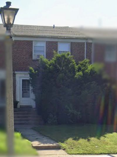 Brick house with a large bush in front and a street lamp.