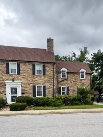 Stone house with dark shutters and a cloudy sky.