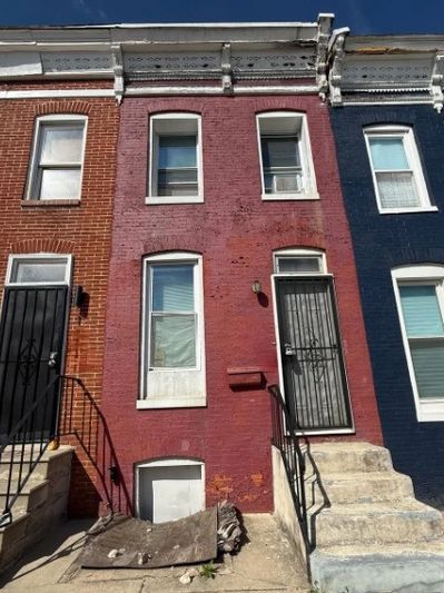 Three connected brick row houses with different colors and stairs.