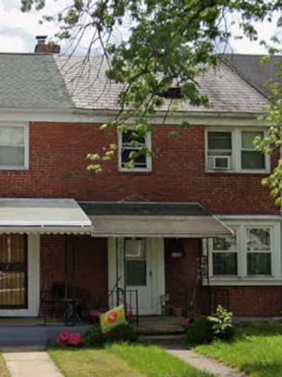 Brick two-story house with a small porch and front yard.