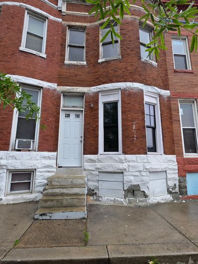 Red brick row house with white trim and concrete steps.