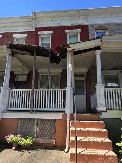 Damaged front porch roof on an old brick house.