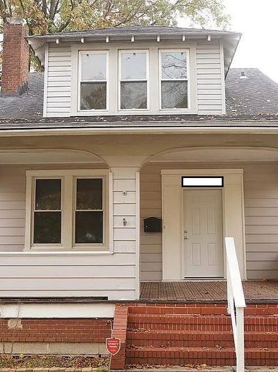 Old house entrance with brick stairs and porch.