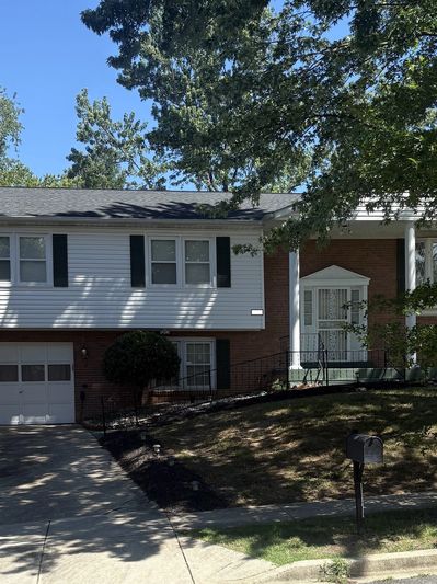 A suburban house with a garage, porch, and tree shadows in the yard.