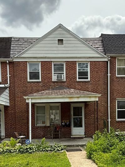 Two-story brick house with porch and shrubs.