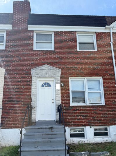 Brick townhouse with white door and two windows.