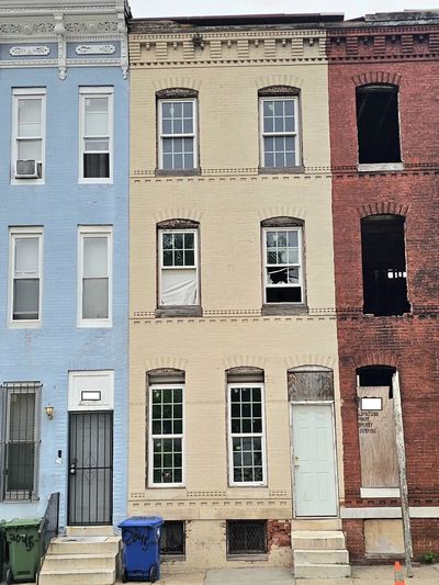 Three adjacent row houses with different colors and conditions.