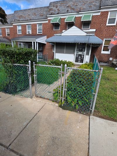Chain-link fence gate in front of a brick house.