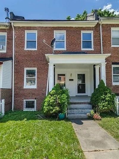 Brick townhouse with front porch and greenery.