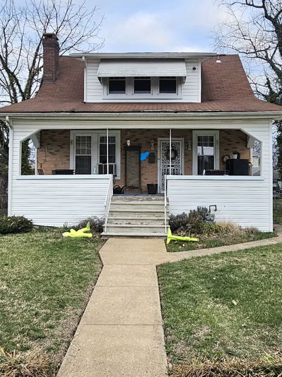 A quaint house with a front porch and stairs leading to the door.