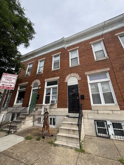 Person walking on sidewalk in front of brick row houses.