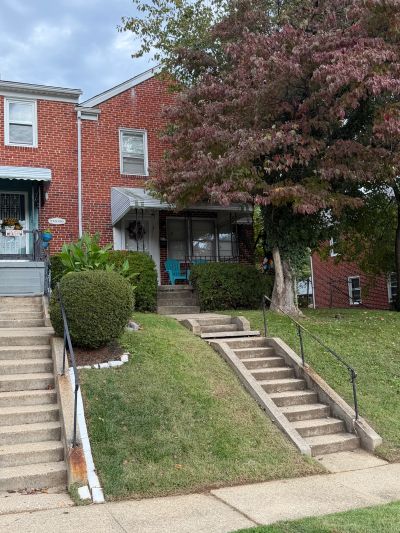 Two brick houses with front steps and a tree with red leaves.