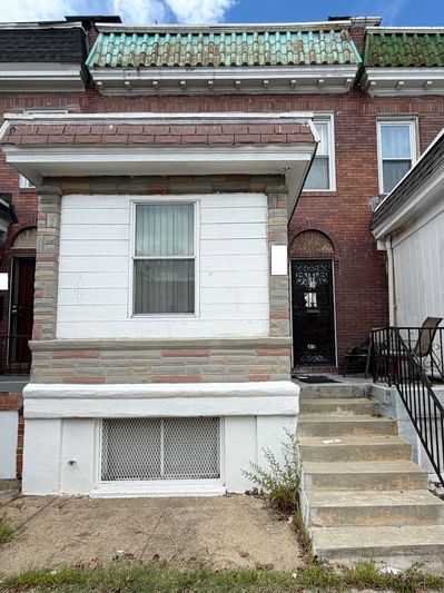 Old brick townhouse with white porch and stairs.