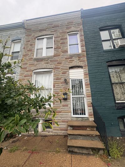 Two-story brick townhouse with steps and a metal gate door.