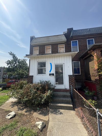Old brick house with boarded-up windows and blue paint mark.
