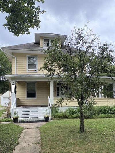 Yellow two-story house with a small front porch and tree.