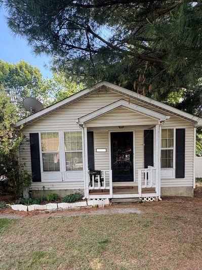 Small white house with black shutters and a front porch.