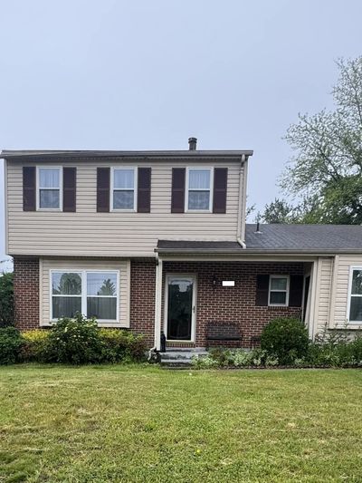 Two-story suburban house with brick and siding exterior and a green lawn.