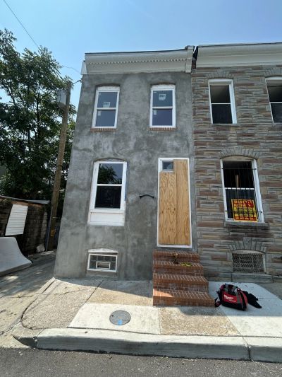 Facade of a row house under renovation with boarded door.