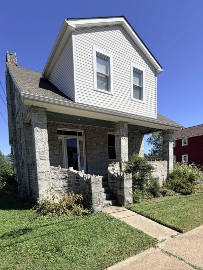 Two-story stone and siding house on a sunny day.