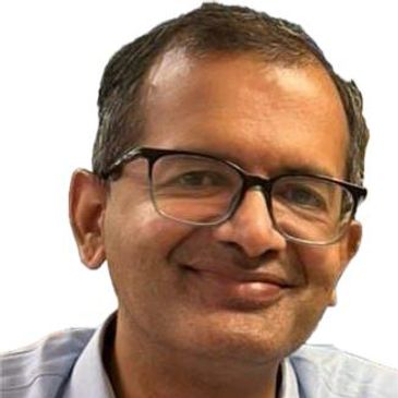 Dr. Sudeep, dermatologist, in glasses and blue shirt, smiling.