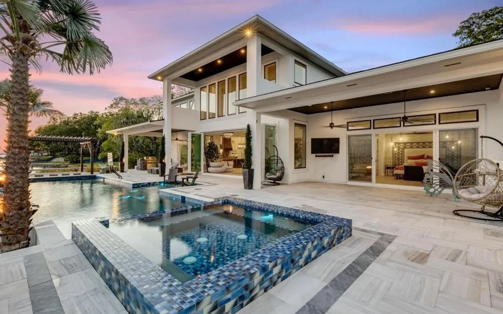 Modern two-story house with a swimming pool and patio under a clear blue sky.