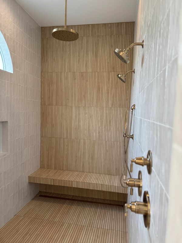 Modern shower area with multiple showerheads and a built-in bench.