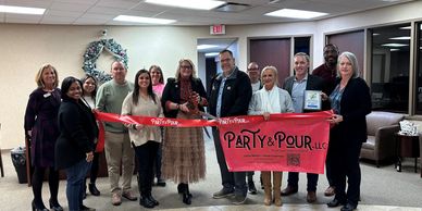 Group of people cutting a red ribbon for Party &amp; Pour LLC opening event.