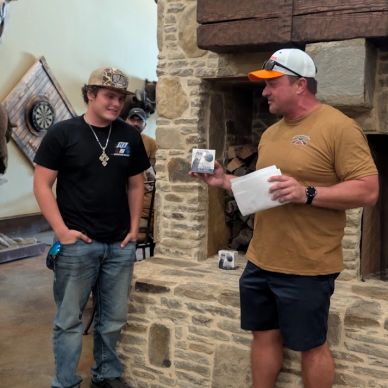 Two men sharing a moment indoors near a stone fireplace.
